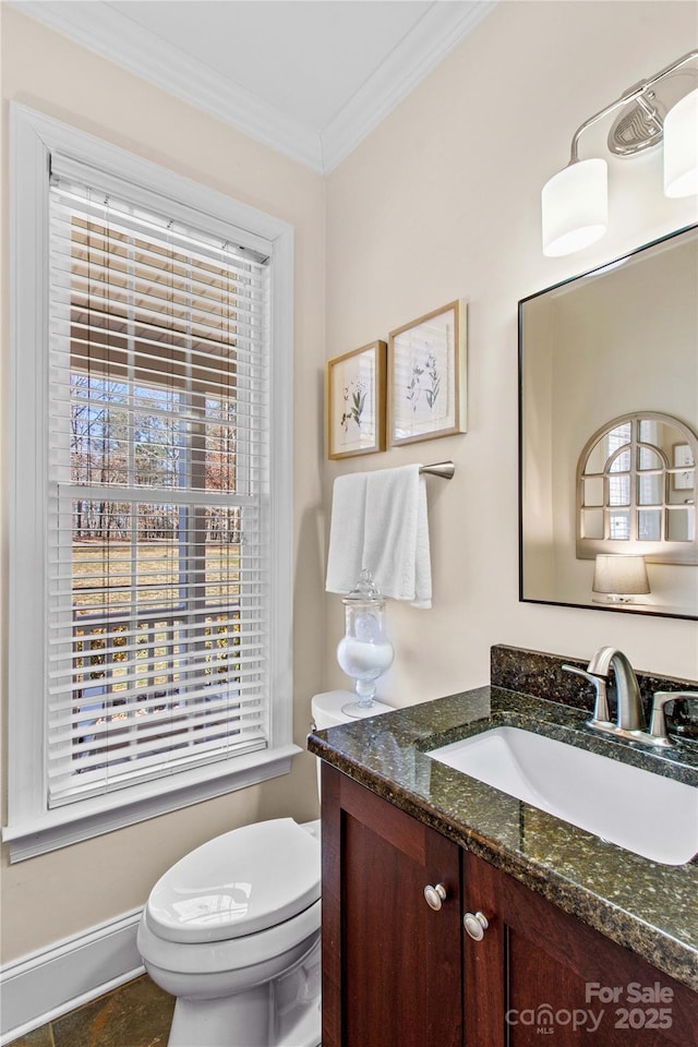 half bath with ornamental molding, baseboards, vanity, and toilet