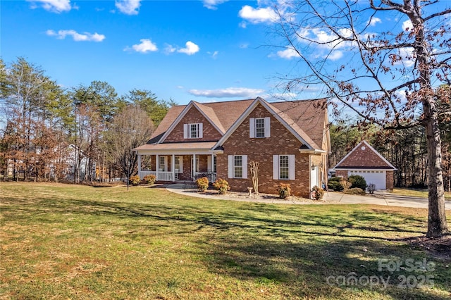 view of front of house featuring brick siding, a detached garage, a porch, a front yard, and an outdoor structure