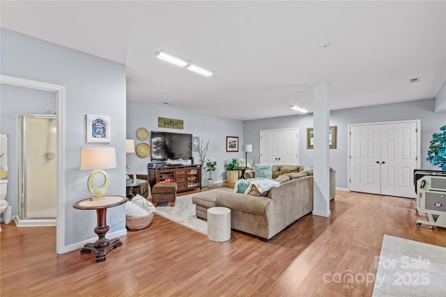 living room with light wood-style flooring, visible vents, and baseboards