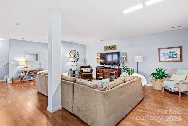 living room with wood finished floors, visible vents, and baseboards