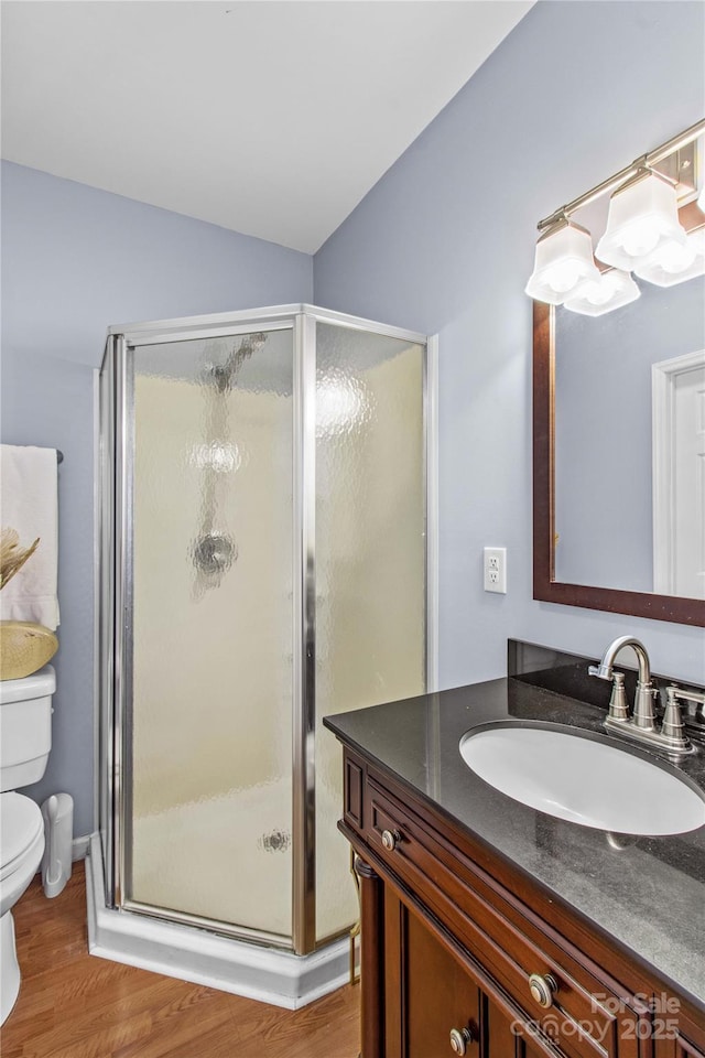 full bath with toilet, a stall shower, vaulted ceiling, vanity, and wood finished floors