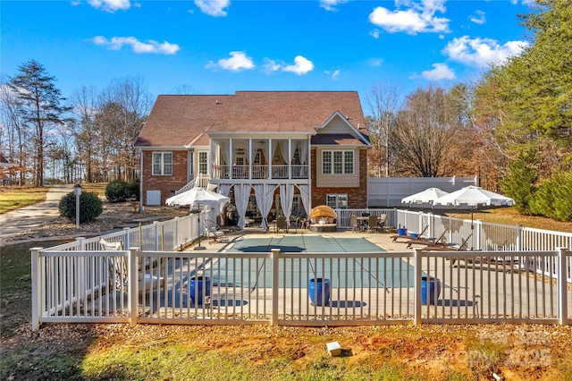 rear view of house featuring a patio, a fenced backyard, brick siding, a sunroom, and a fenced in pool