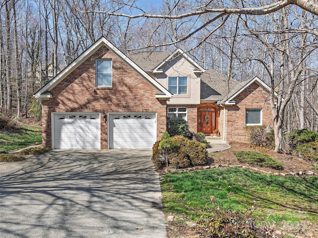 traditional home with stucco siding, aphalt driveway, roof with shingles, an attached garage, and brick siding