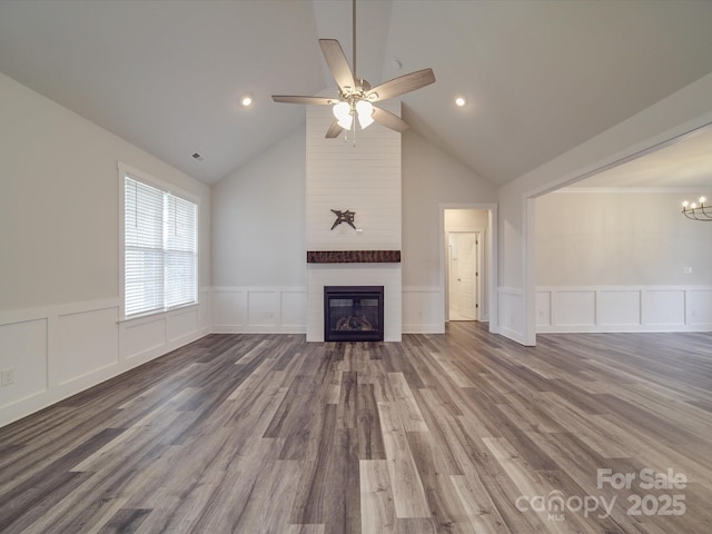 unfurnished living room with wood-type flooring, vaulted ceiling, ceiling fan with notable chandelier, and a fireplace