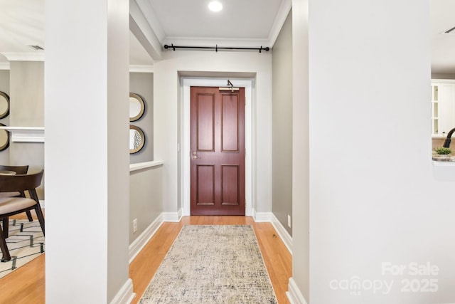 doorway to outside featuring ornamental molding and light hardwood / wood-style floors