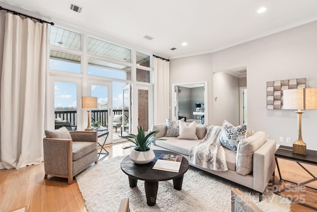 living room with crown molding and light hardwood / wood-style floors