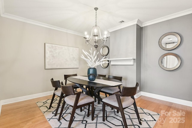 dining space with ornamental molding, a chandelier, and light hardwood / wood-style flooring