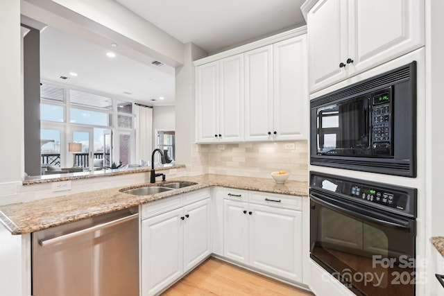 kitchen with light stone counters, sink, black appliances, and white cabinets