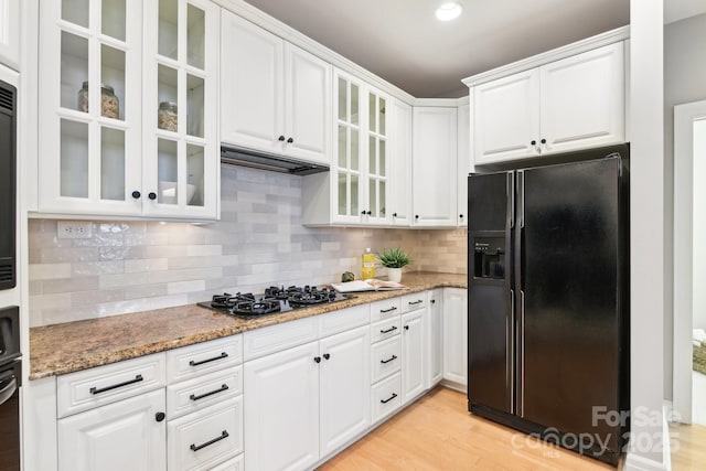 kitchen featuring white cabinetry, light stone counters, gas cooktop, and black fridge