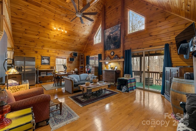 living room with ceiling fan, wood ceiling, wooden walls, and light hardwood / wood-style flooring