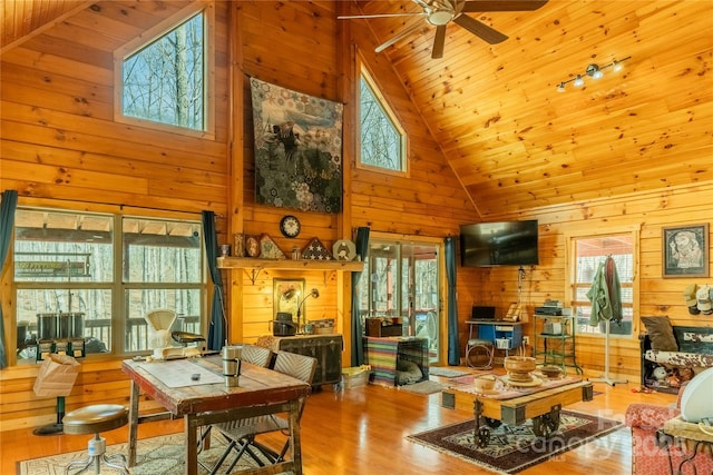 living room featuring ceiling fan, hardwood / wood-style floors, high vaulted ceiling, wooden ceiling, and wood walls