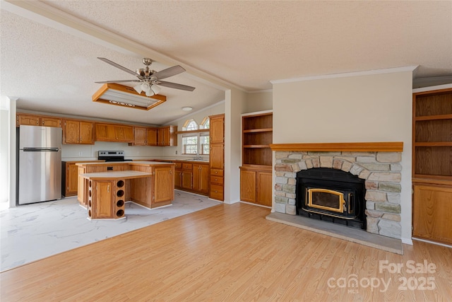 kitchen with sink, light hardwood / wood-style flooring, a textured ceiling, appliances with stainless steel finishes, and a kitchen island