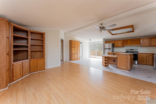 kitchen with lofted ceiling, appliances with stainless steel finishes, a center island, a textured ceiling, and light wood-type flooring