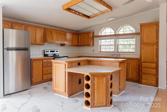 kitchen featuring a textured ceiling, ornamental molding, custom range hood, a kitchen island, and stainless steel appliances