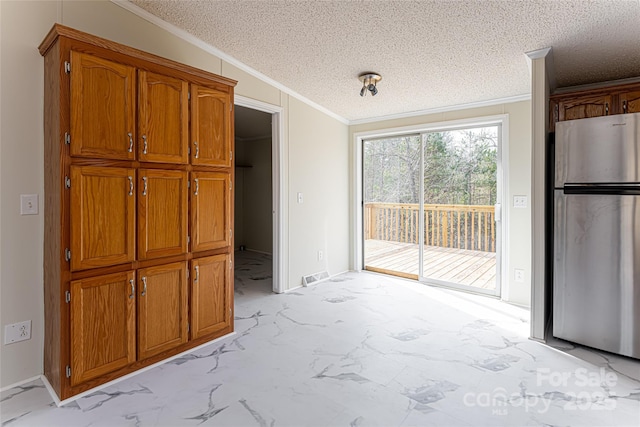 kitchen with stainless steel refrigerator, ornamental molding, and a textured ceiling