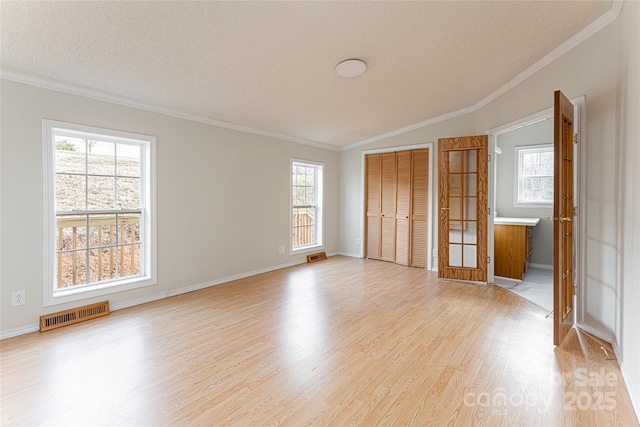 unfurnished bedroom with multiple windows, light hardwood / wood-style flooring, and a textured ceiling