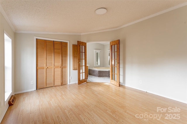 unfurnished bedroom featuring french doors, ornamental molding, light hardwood / wood-style floors, and a closet