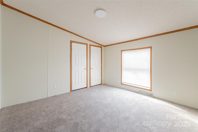 carpeted empty room with crown molding, vaulted ceiling, and a textured ceiling