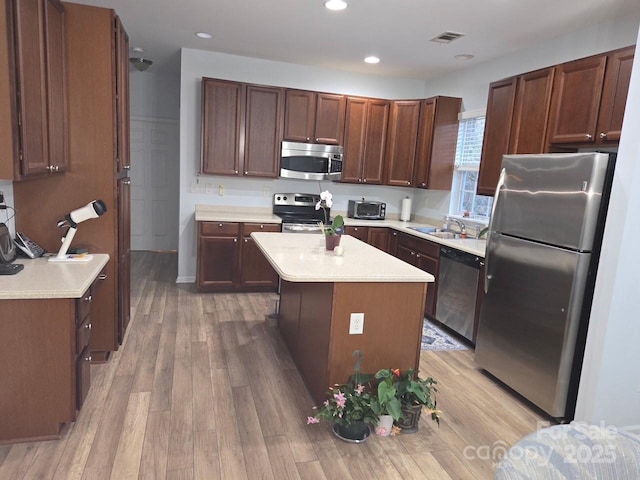 kitchen with sink, dark brown cabinets, stainless steel appliances, light hardwood / wood-style floors, and a kitchen island