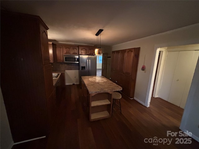 kitchen featuring decorative light fixtures, appliances with stainless steel finishes, dark hardwood / wood-style flooring, a kitchen breakfast bar, and a kitchen island