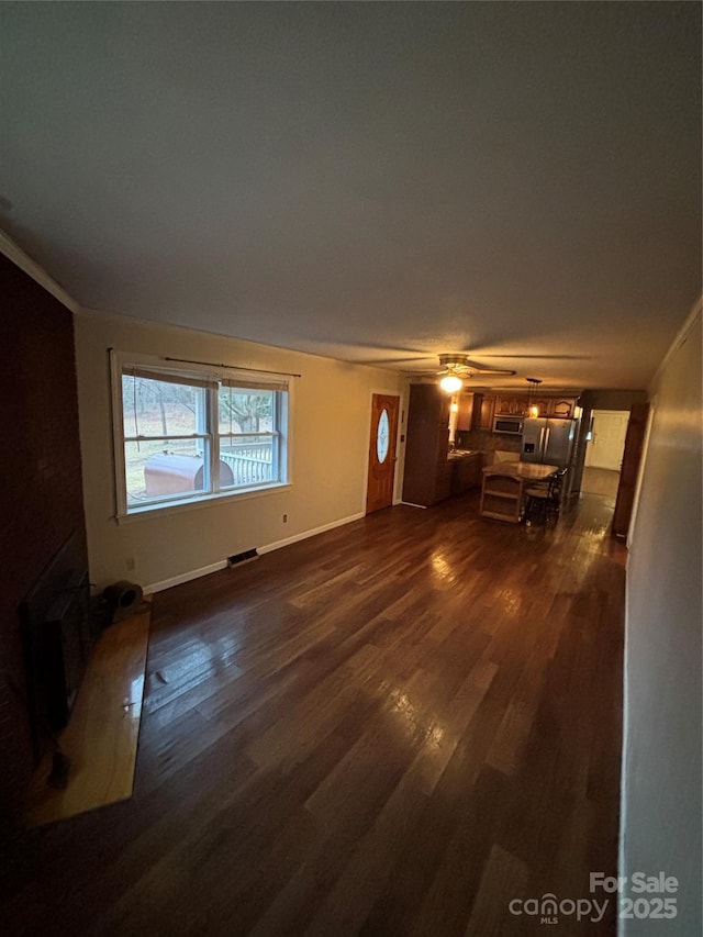 unfurnished living room featuring crown molding, dark hardwood / wood-style floors, and ceiling fan