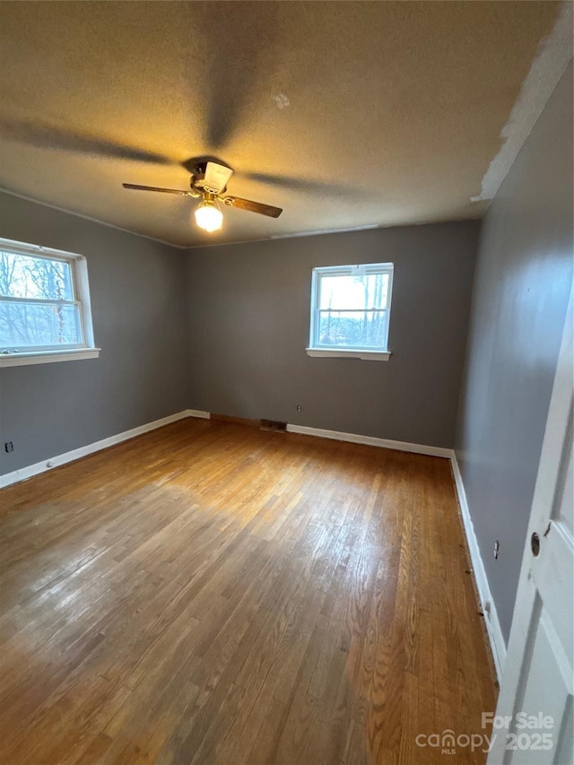 unfurnished room featuring hardwood / wood-style flooring, ceiling fan, and a textured ceiling