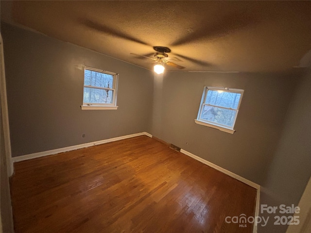 unfurnished room featuring wood-type flooring, a wealth of natural light, ceiling fan, and a textured ceiling