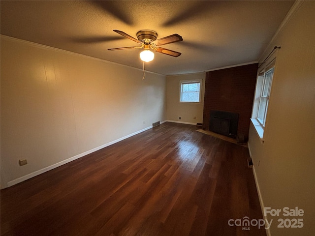 unfurnished living room with ornamental molding, dark hardwood / wood-style floors, a brick fireplace, and a textured ceiling