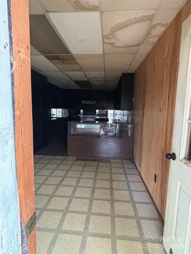 kitchen featuring a paneled ceiling and wood walls