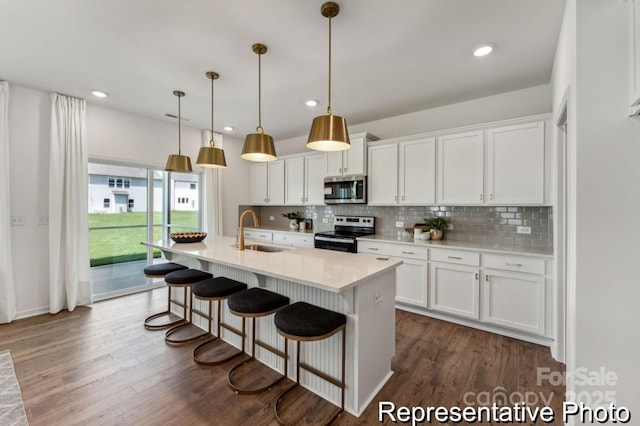 kitchen featuring sink, stainless steel appliances, tasteful backsplash, white cabinets, and decorative light fixtures