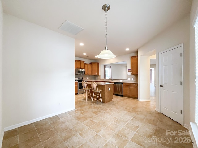 kitchen with a center island, appliances with stainless steel finishes, a kitchen breakfast bar, pendant lighting, and backsplash