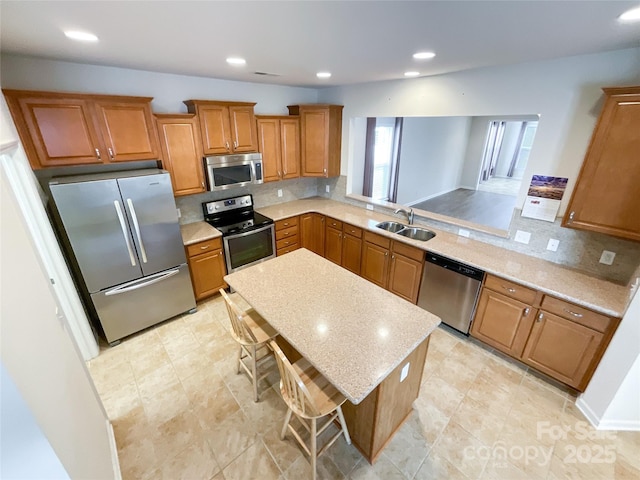 kitchen with sink, stainless steel appliances, tasteful backsplash, a kitchen bar, and kitchen peninsula