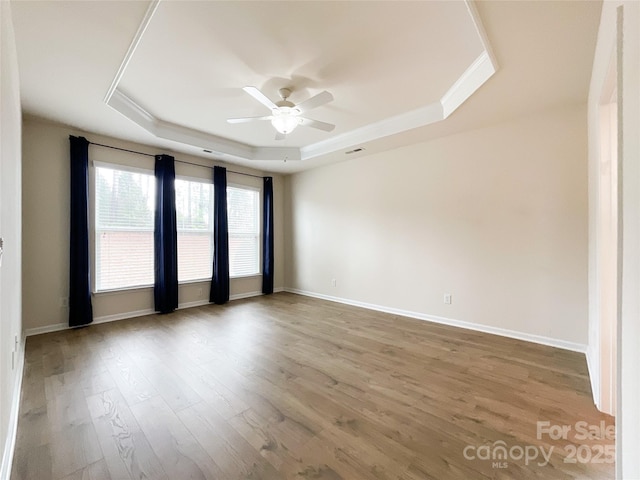 spare room with crown molding, hardwood / wood-style flooring, a raised ceiling, and ceiling fan