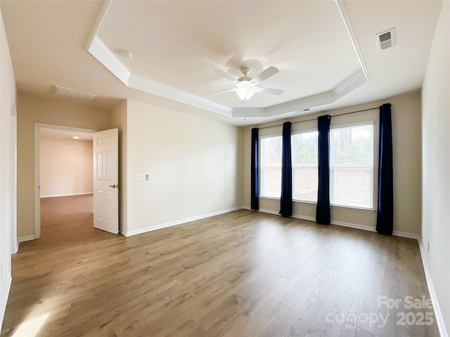 unfurnished room featuring light hardwood / wood-style flooring, a raised ceiling, and ceiling fan