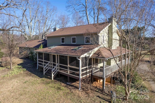 back of property with a sunroom, a shingled roof, and a chimney