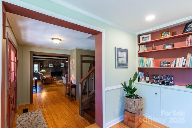 hallway featuring light wood-style flooring, stairway, and crown molding