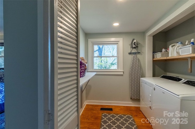 clothes washing area featuring visible vents, separate washer and dryer, wood finished floors, laundry area, and baseboards