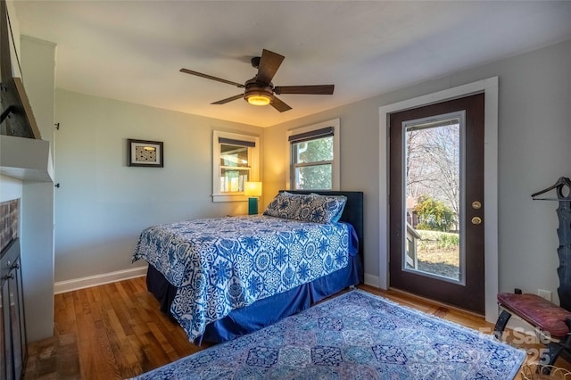 bedroom with a fireplace, ceiling fan, baseboards, and wood finished floors