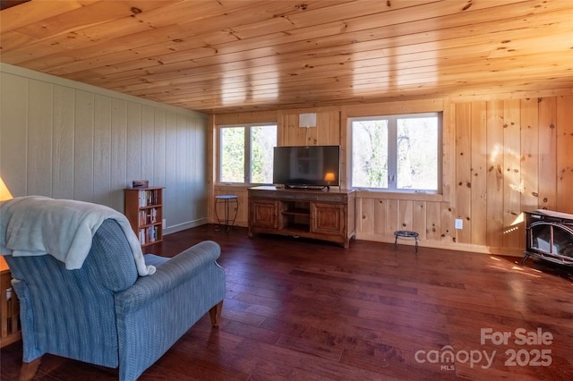 living area featuring a wood stove, wood ceiling, baseboards, and dark wood-type flooring