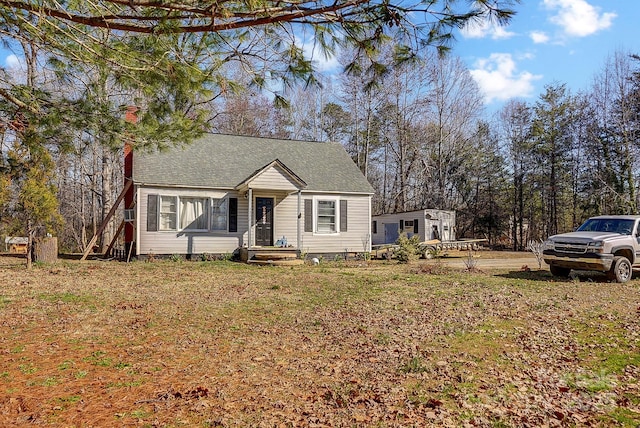 view of front of home with roof with shingles and a front lawn