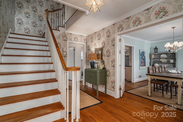 stairs with ornamental molding, an inviting chandelier, and wood-type flooring