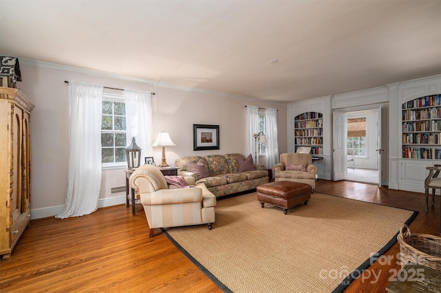 living room featuring light hardwood / wood-style floors, built in shelves, and ornamental molding