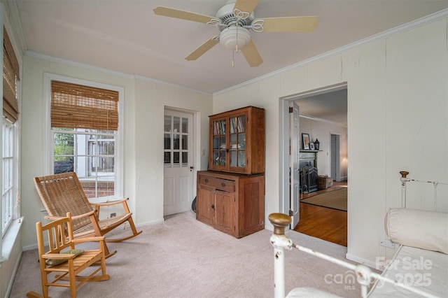 sitting room with crown molding, light colored carpet, and ceiling fan