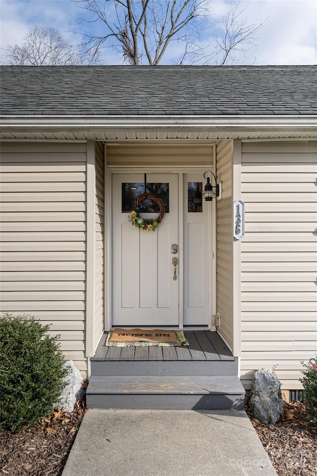 view of exterior entry with a shingled roof