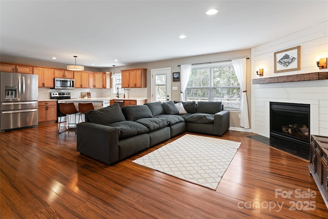 living area featuring dark wood-style floors, recessed lighting, and a fireplace with flush hearth