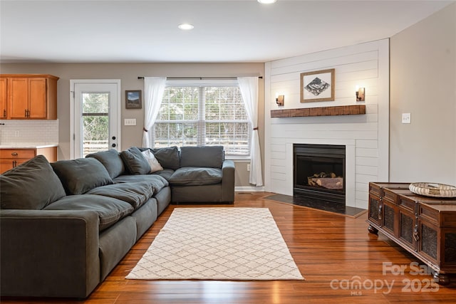 living room featuring recessed lighting, a fireplace, and dark wood finished floors