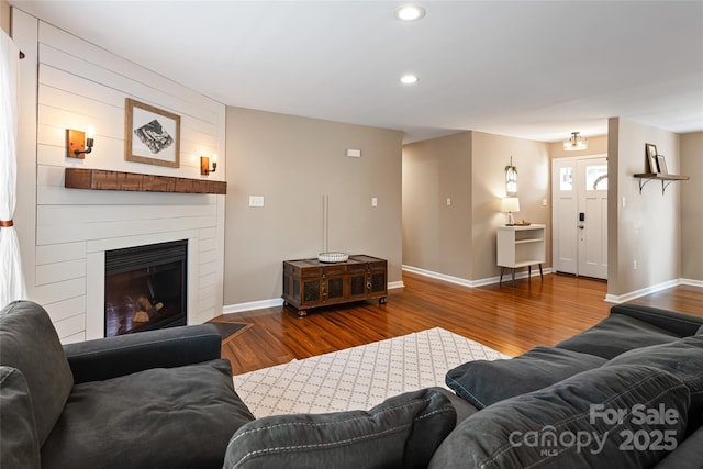 living room featuring a fireplace, baseboards, wood finished floors, and recessed lighting