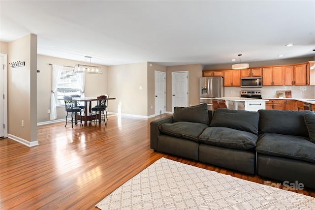 living room with light wood finished floors, recessed lighting, and baseboards