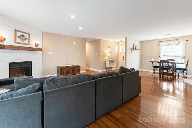 living room featuring a large fireplace, baseboards, dark wood finished floors, and recessed lighting