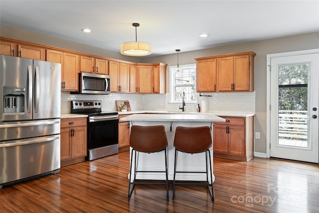 kitchen featuring dark wood finished floors, stainless steel appliances, light countertops, and decorative light fixtures